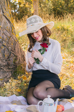 Chica joven con moda vintage sosteniendo una rosa entre las manos y sonriendo en una cita 
