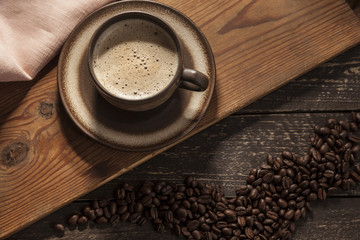 Coffee background. Ground coffee with foam with coffee beans on a wooden dark table.