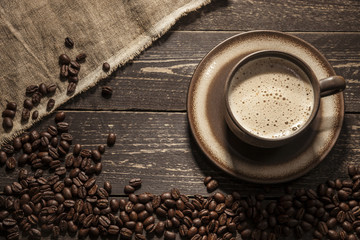 Coffee background. Ground coffee with foam with coffee beans on a wooden dark table with jute bag. 