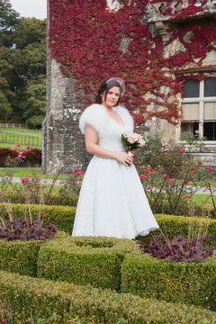Bride has photos taken in formal garden during autumn