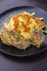 Braised rabbit with Italian pasta tagliatelle and Gérin chanterelles mushrooms on a black plate. homemade food