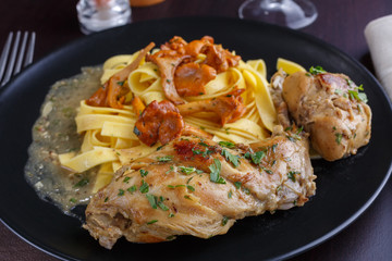 Braised rabbit with Italian pasta tagliatelle and Gérin chanterelles mushrooms on a black plate. homemade food