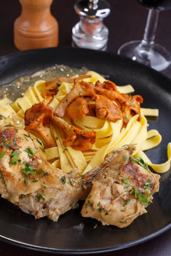 Tagliatelle with chanterelles and stewed rabbit on black terelke. side and top view. Italian pasta homemade food. setout