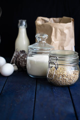 Ingredients for oatmeal cookies (oat flakes, sugar, eggs, milk) on the wooden background or table. Daily product