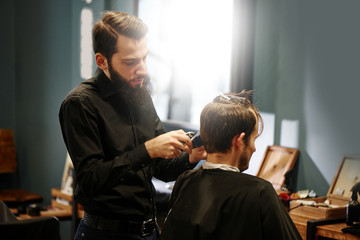 Barber man cutting a client's hair clippers in the barbershop