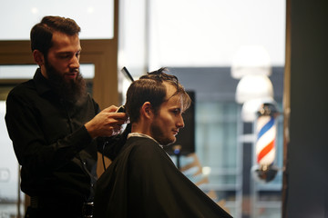 Barber man cutting a client's hair clippers in the barbershop