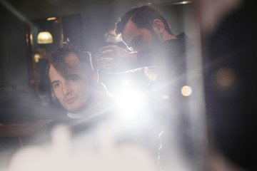 Fototapeta premium Male hairdresser cuts client with scissors in the barbershop black-and-white photo