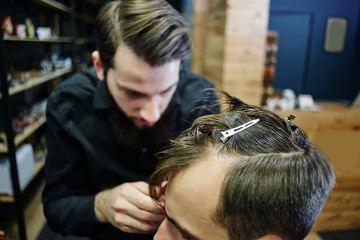 The Barber man in the black shirt in the process of cutting a customer in the barbershop