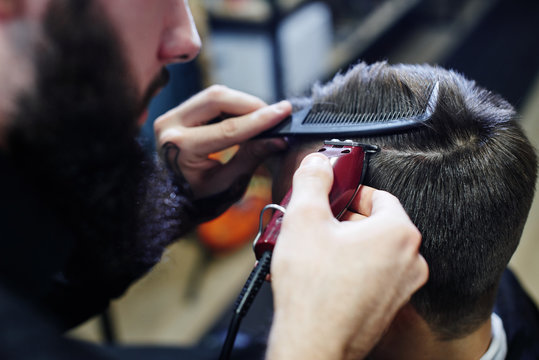 The Barber makes the man parted the customer an electric trimmer in a Barbershop