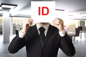 businessman in suit hiding face behind sign id