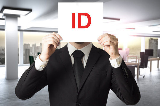 businessman in suit hiding face behind sign id