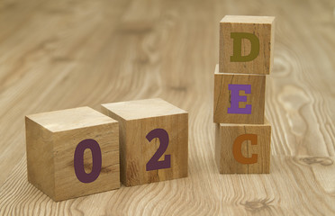 Cube shape calendar for December 02 on wooden surface.