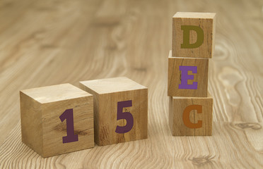 Cube shape calendar for December 15 on wooden surface.