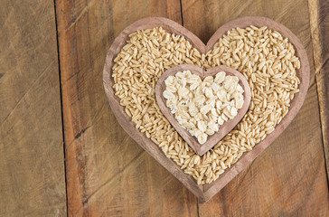 Seeds and oat flakes in wooden bowl shaped heart