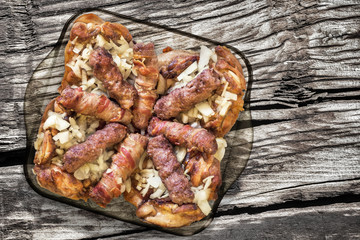 Grilled Minced Meat Loafs Cevapcici And Chicken Thighs with Chopped Onion In Glass Baking Pan Set On Old Wood