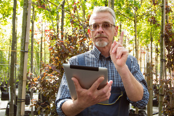Fototapeta premium Online Store Manager with a clipboard in hands on a background of a greenhouse