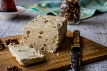 Slices of Halva with peanut walnut and tea on a wooden surface.