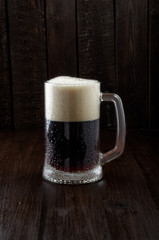Beer mug with drops and foam on dark background