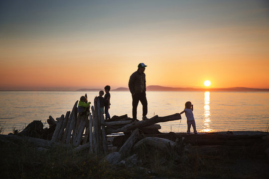 Father With Children At Beach During Sunset