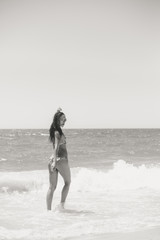 Black and white back view of beautiful woman in bikini on the sunny beach outdoors background.