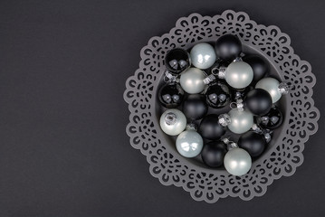 festliche Dekoration - Teller mit weißen und schwarzen Weihnachtskugeln auf dunklem Untergrund