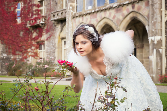 Bride smells the roses outside country house  with autumn colour