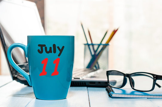 July 11th. Day 11 of month, color calendar on morning coffee cup at business workplace background. Summer concept. Empty space for text