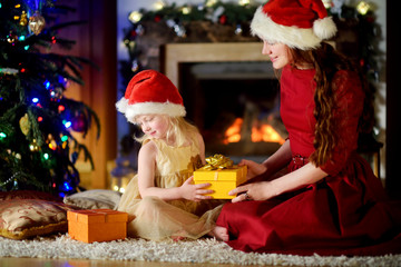 Happy little girl getting a Christmas gift from her mommy
