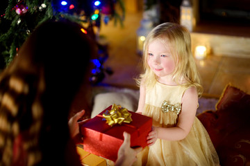 Happy little girl getting a Christmas gift from her mommy