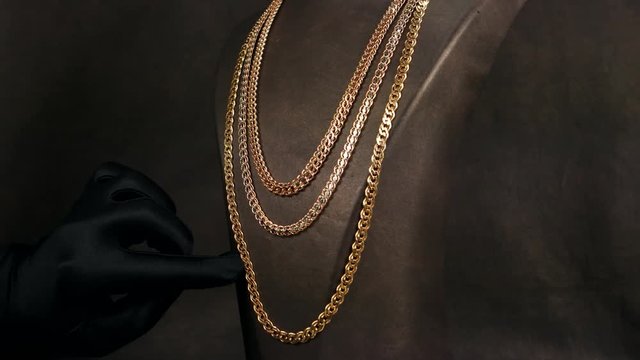 Jewelry store, The palm of the glove in black shows gold chains on a dummy, jewelery exhibition, the seller in gloves shows customers jewelry, expensive jewelry for sale, gold chains expensive present
