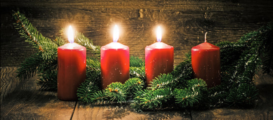 Dritter Advent: drei leuchtende Kerzen vor einem Holzhintergund - 125538364
