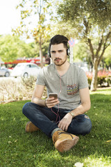 Naklejka na ściany i meble Young man using a smart phone and listening to the music with headphones