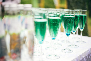 A lot of wine glasses with a cool delicious champagne or white wine at the bar. Blue Alcohol background.