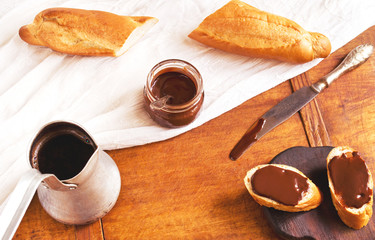 Breakfast with coffee, French baguette and chocolate on kitchen table
