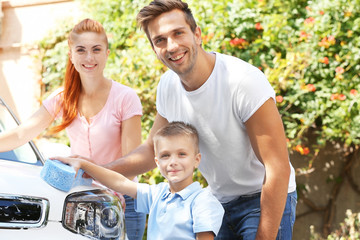 Happy family washing car on street