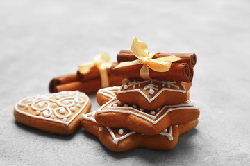 Tasty gingerbread cookies and cinnamon sticks on textured background