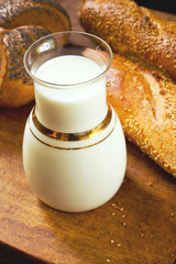 Fresh milk with French baguettes and poppy seed loaf on a wooden table