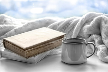 Hot drink with books and plaid on windowsill