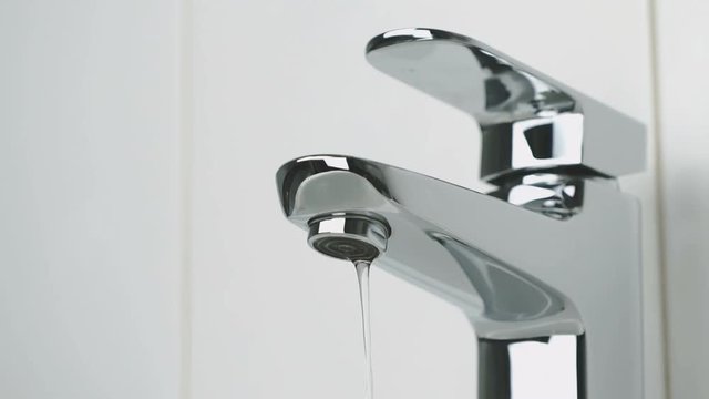 Weak stream of water pouring from the chrome tap