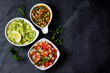 Traditional Latin American sauces Guacamole, Salsa, chili Pebre, slate background