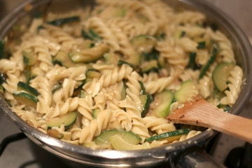 Cooking pasta with zucchini and melted cheese in a pan. Selective focus. 