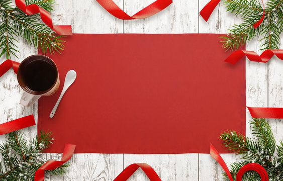 Wooden table with christmas decorations. Free space for christmas card text. Top view of table with table cloth, christmas tree, decorative strips and cup of tea.
