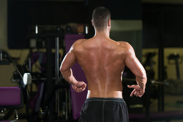 Fototapeta na wymiar Young Bodybuilder Flexing Rear Double Biceps Pose