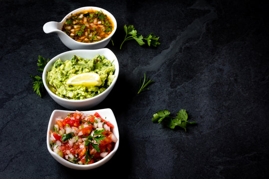 Traditional Latin American sauces Guacamole, Salsa, chili Pebre, slate background