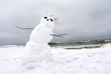 crazy, melting snowman on a winter beach