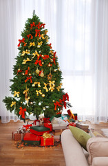 Beautiful Christmas tree and boxes with presents against window