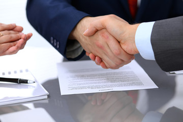 Obraz premium Two business man shaking hands to each other above signed contract