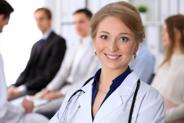 Obraz premium Happy doctor woman on the background doctor and many patients