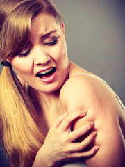 woman scratching her itchy arm with allergy rash