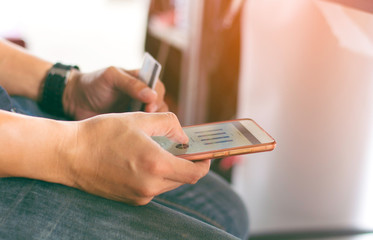 Selective focus young man using old phone with credit card for business investment